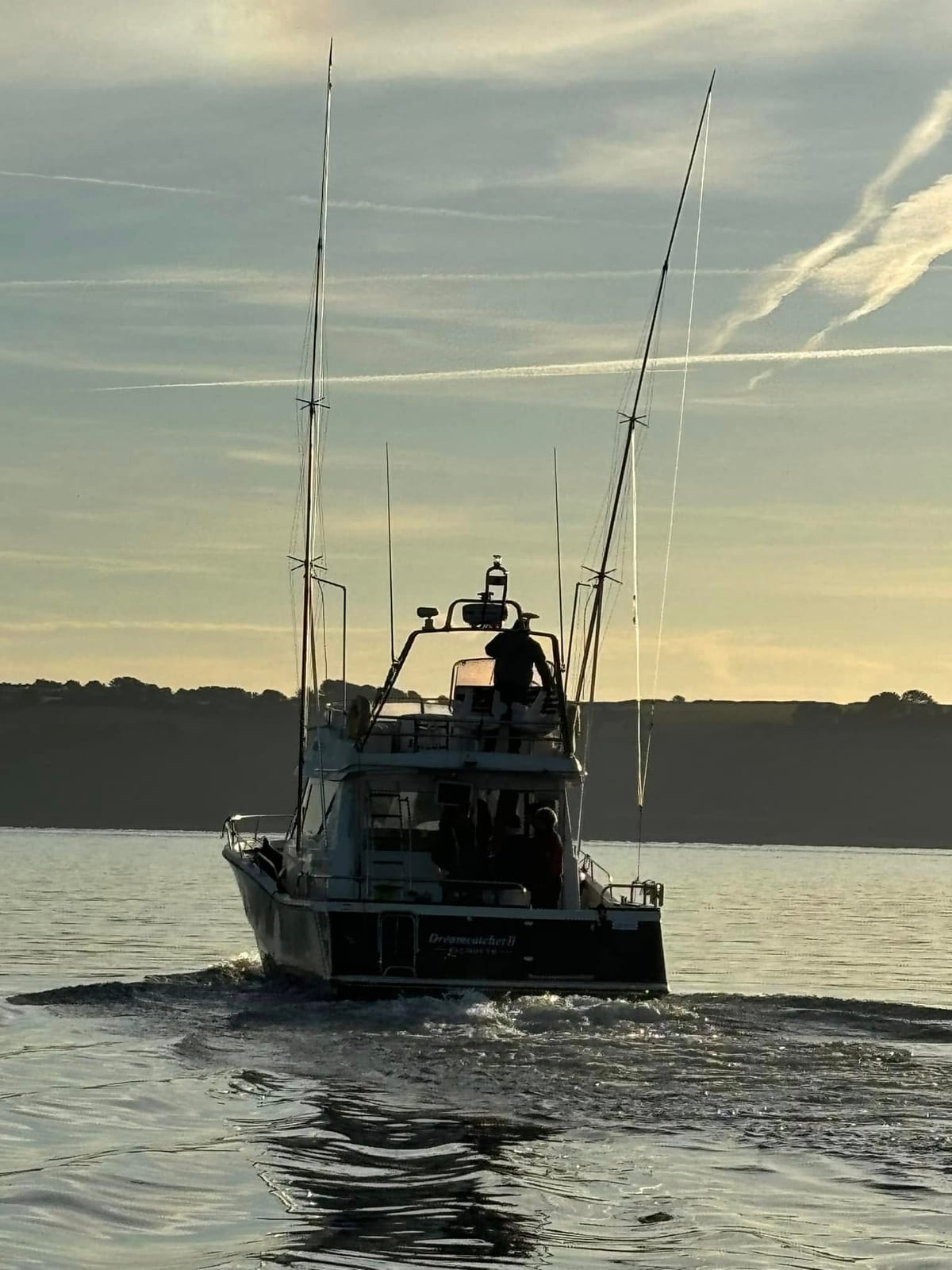 Dreamcatcher heading out of Falmouth at first light, outriggers up, crew on the flybridge
