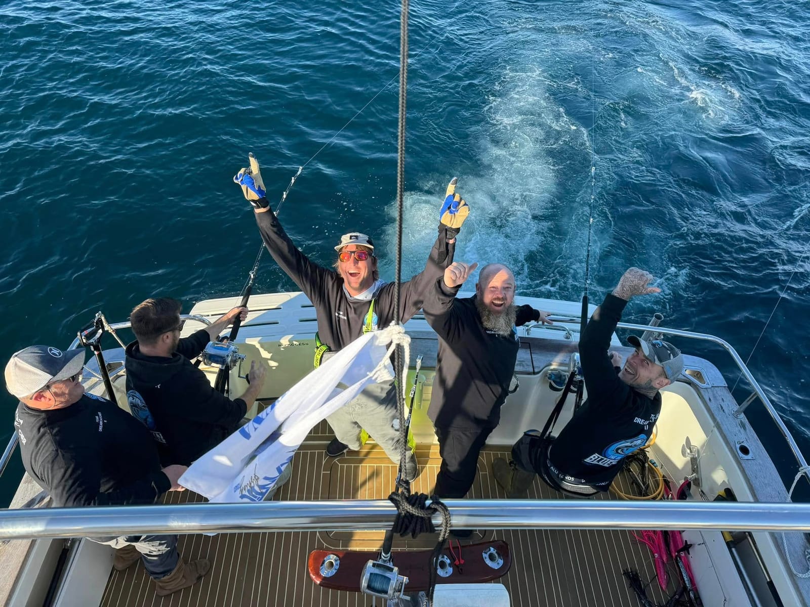 Looking down on the teak deck of Dreamcatcher with four anglers celebrating
