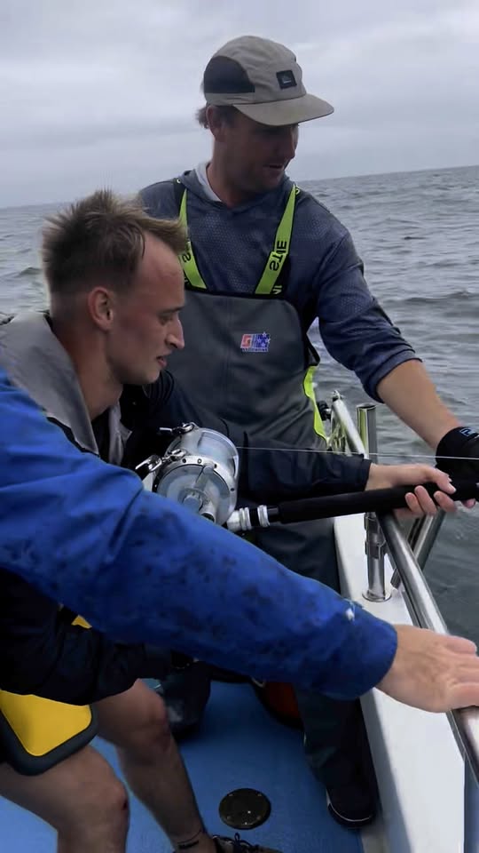 An angler in a fighting harness bends into a bluefin tuna while the deckhand watches the line